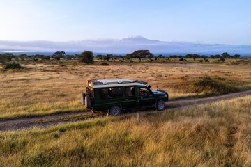 amboseli-national-park-kenya-suv-with-open-roof-is-driving-through-savannah-afternoon-safari-game-drive-with-wildebeest-reserve-kenya-africa_431724-16025